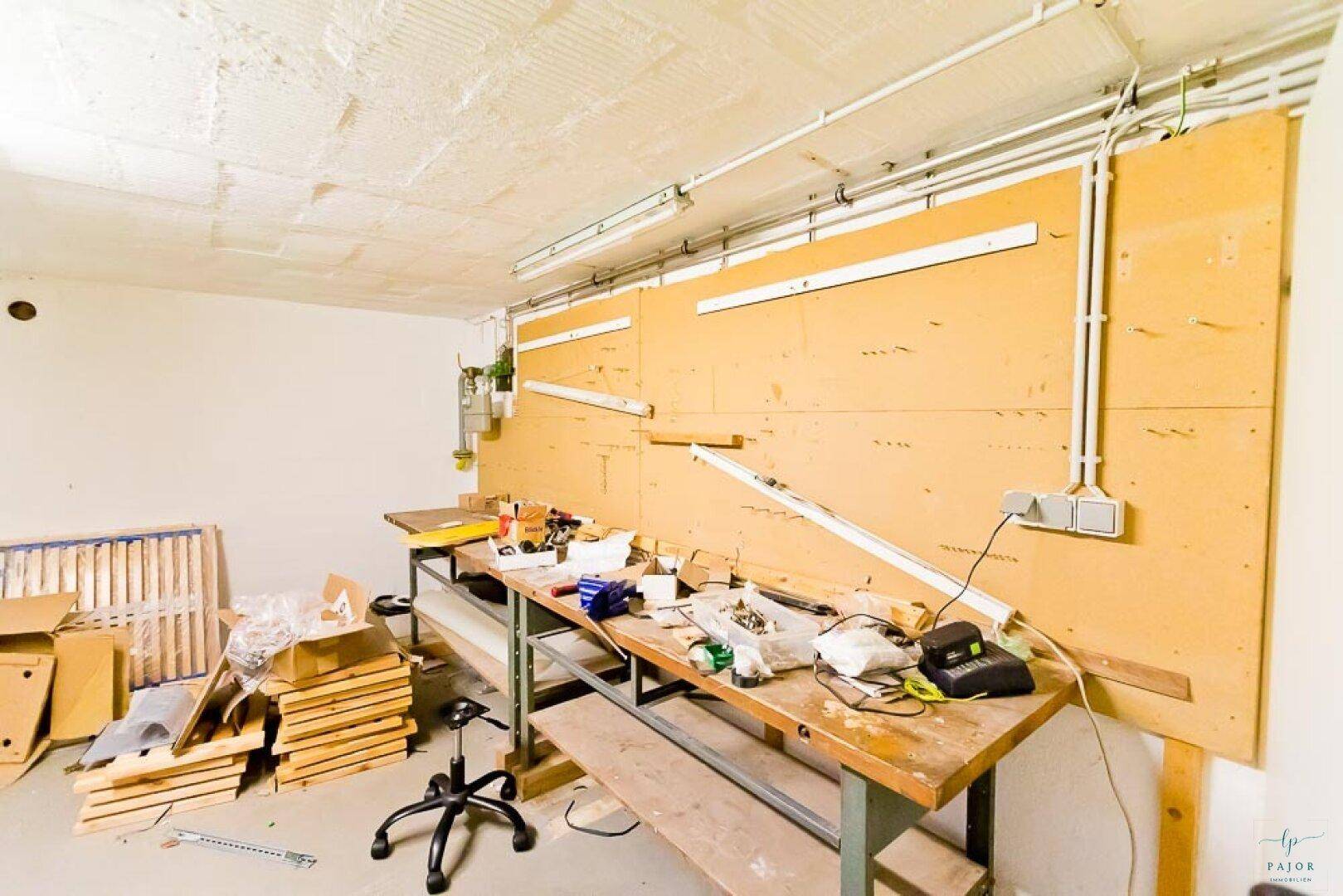 Geräumiger Werkstattbereich im Keller mit großer Arbeitsplatte und viel Platz.