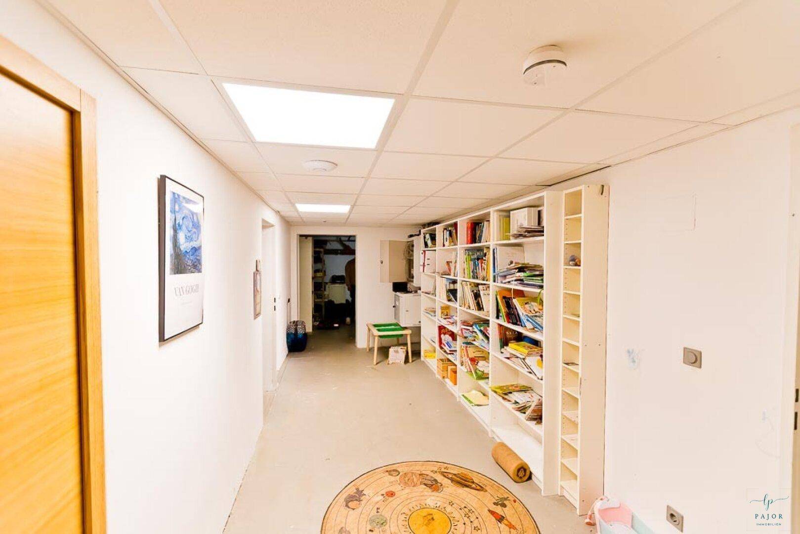 Heller Kellerflur mit einem großen Bücherregal und praktischem Stauraum.