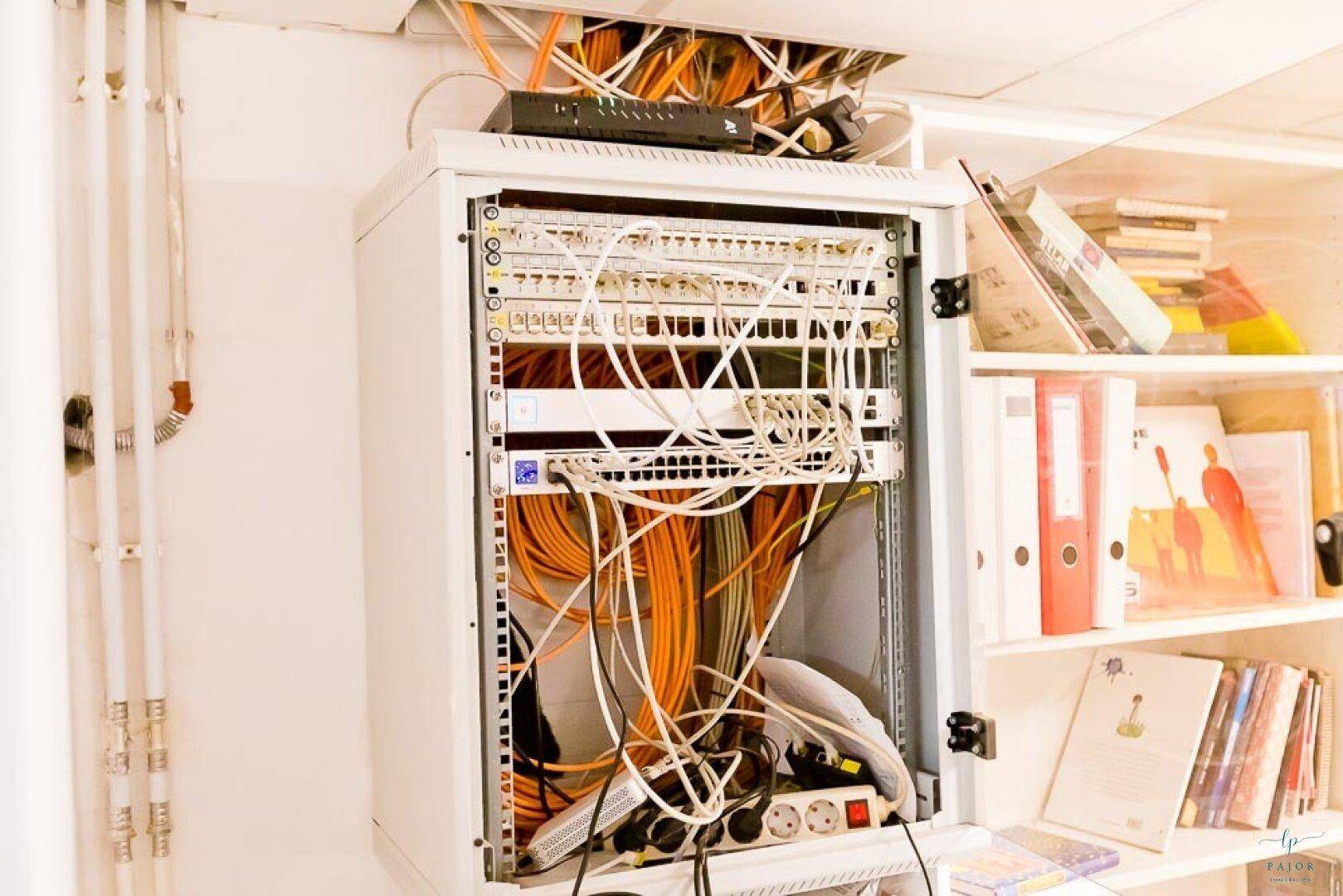 Technischer Raum mit einem Serverschrank und komplexer Netzwerkverkabelung.