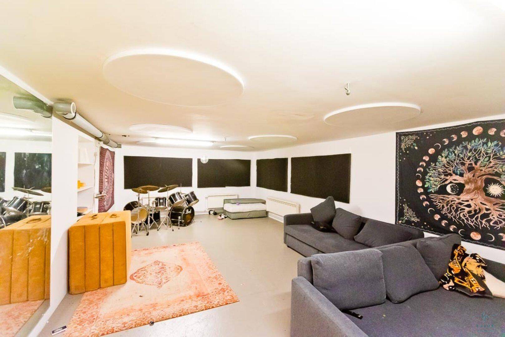 Großer Kellerraum, eingerichtet als Musikzimmer mit Schlagzeug und Sofa.