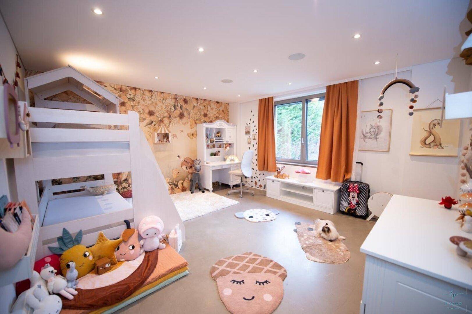 Freundliches Kinderzimmer mit Etagenbett, Schreibtisch und verspielter Tapete.