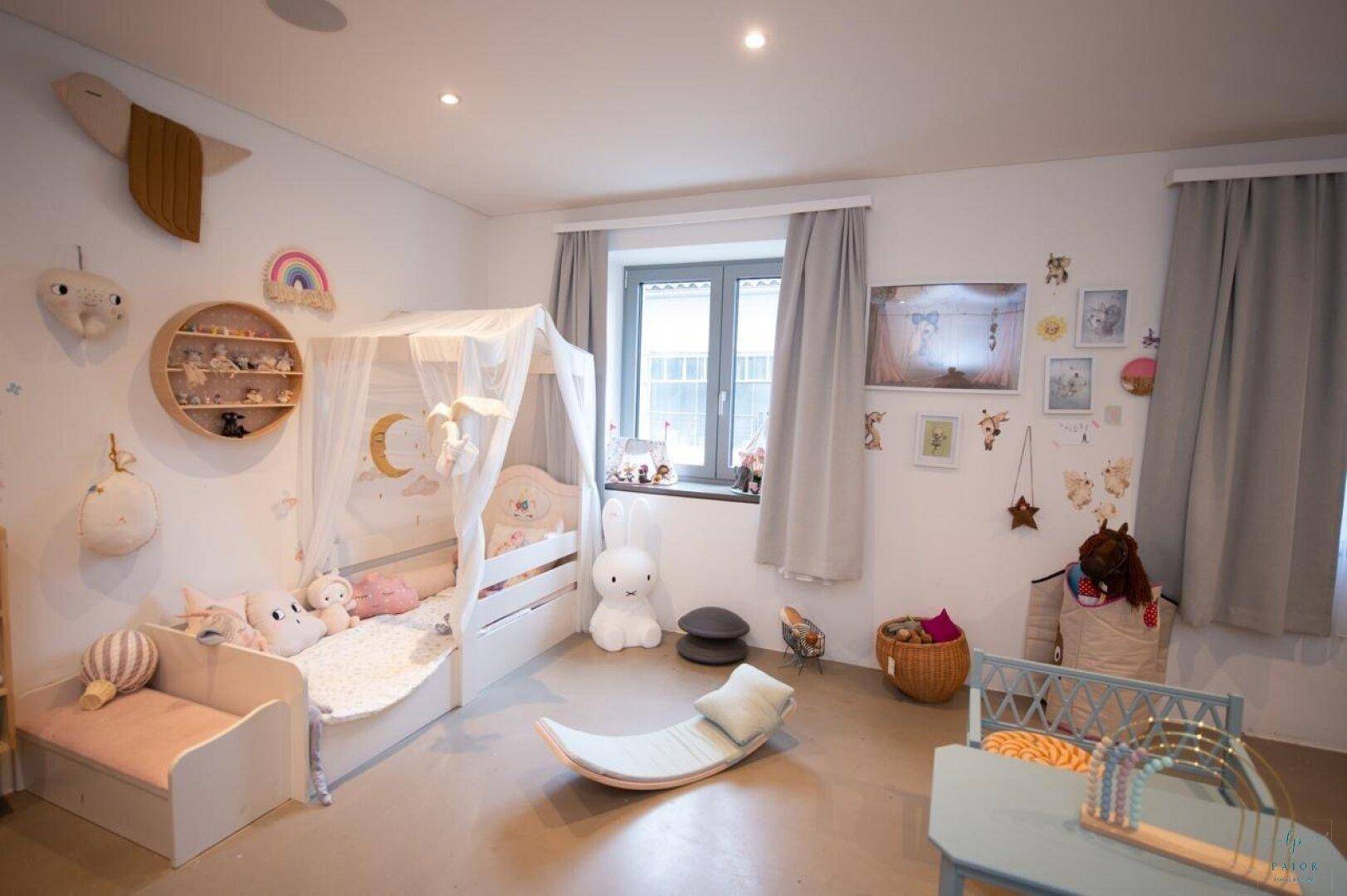 Charmantes Kinderzimmer mit Himmelbett, vielen Spielsachen und natürlichem Lichteinfall.