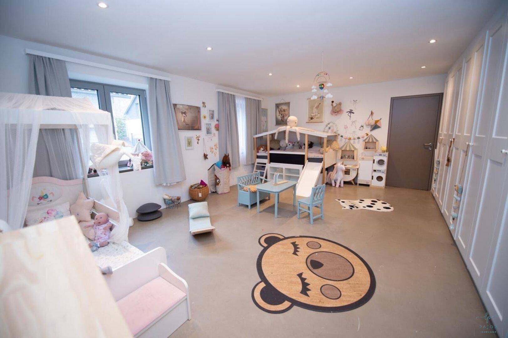 Geräumiges Kinderzimmer mit Spielbereich, Bett und praktischen Einbauschränken.