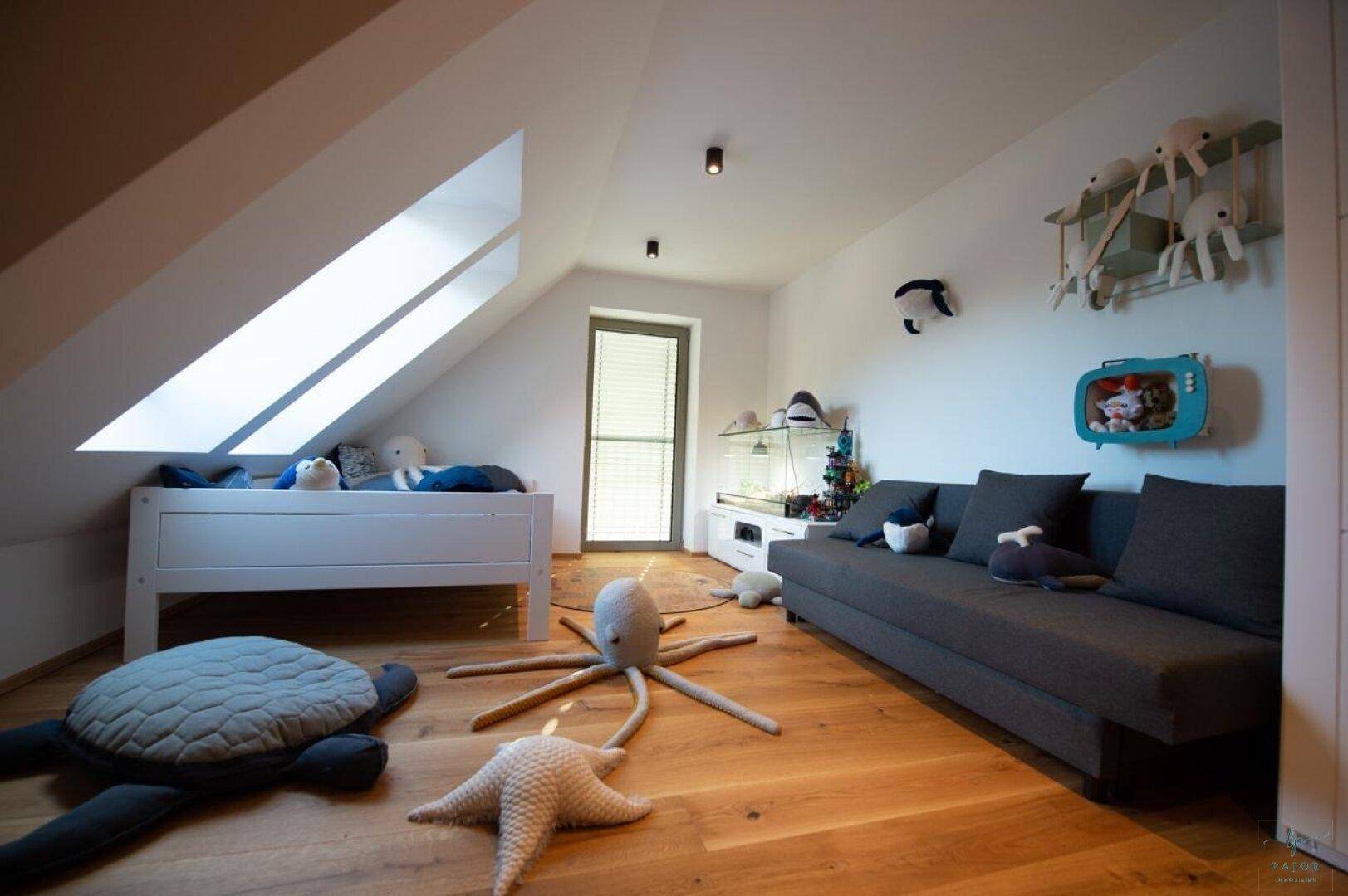 Dachgeschoss-Schlafzimmer mit schräger Decke, Dachfenster und gemütlichem Sofa.