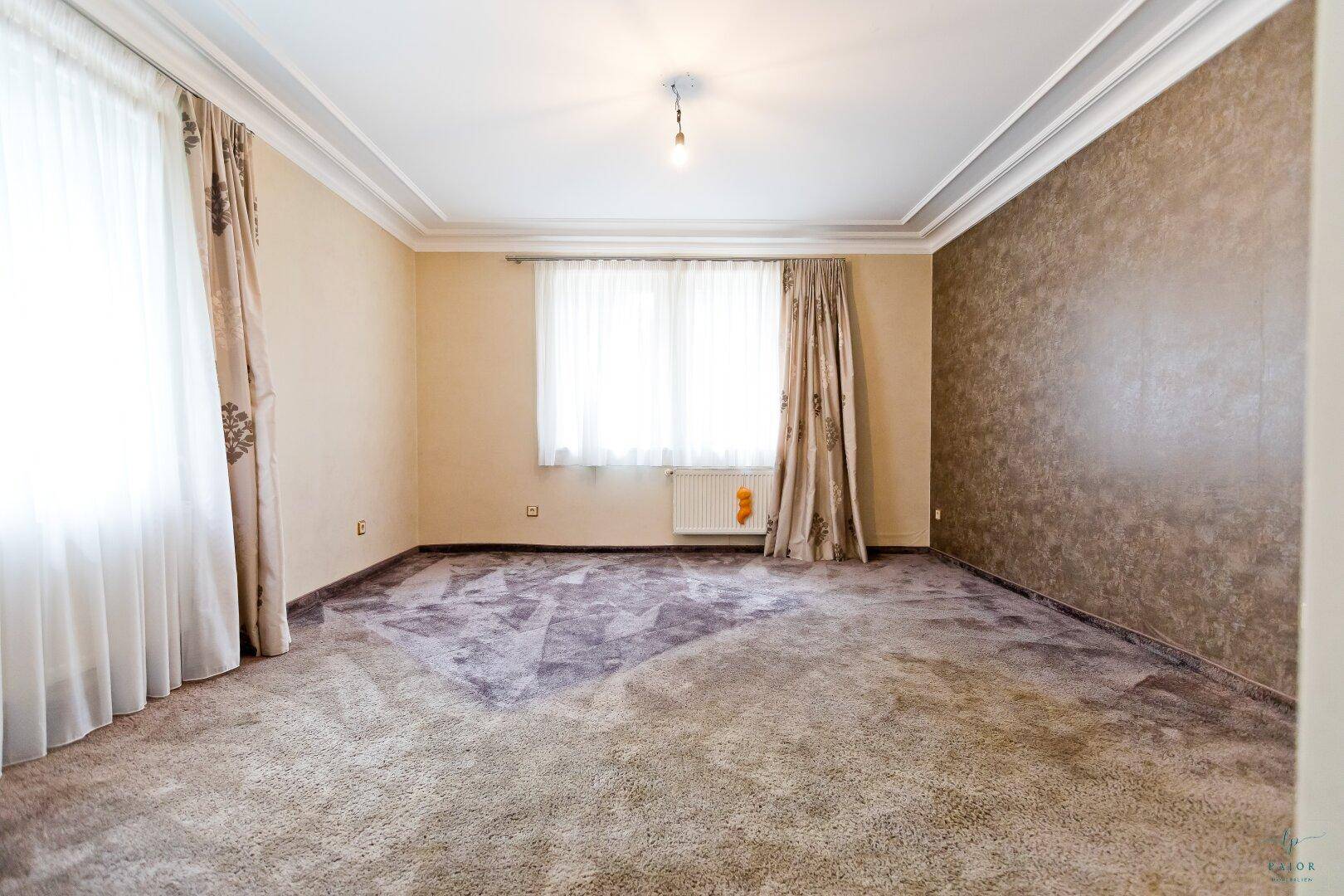 Geräumiges Schlafzimmer mit Teppichboden, großen Fenstern und dekorativer Wandgestaltung.