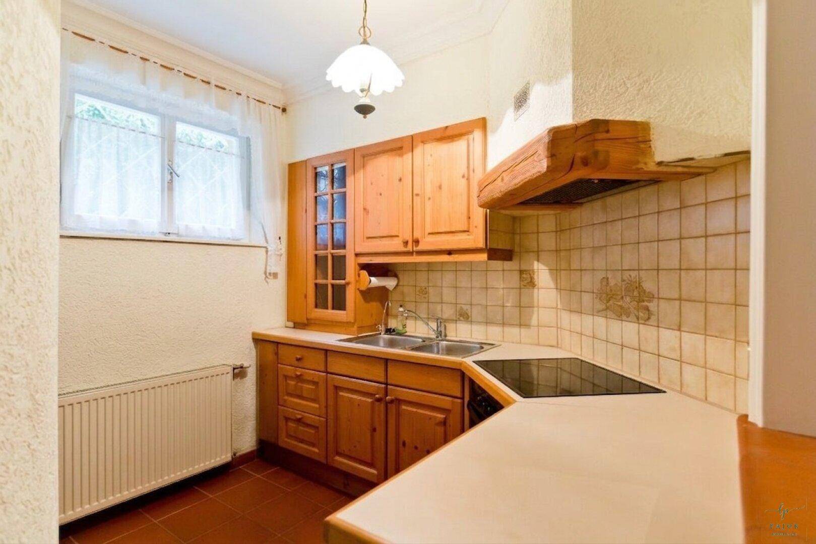 Traditionelle Küche mit Holzelementen, Kochfeld und Fliesen-Rückwand.