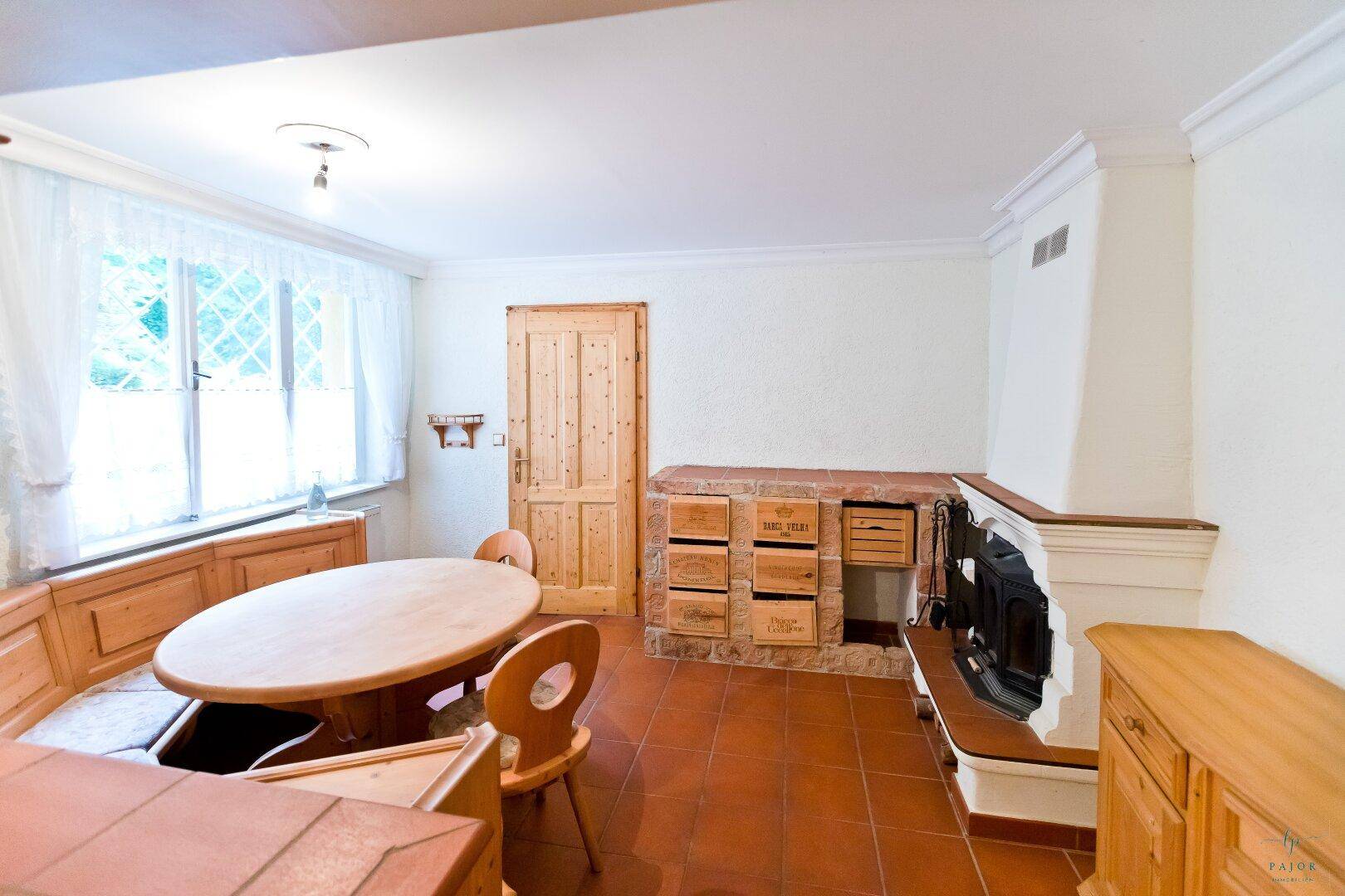 Essbereich mit Holzeinbauten, Kamin und Fenster mit Blick in den Garten.