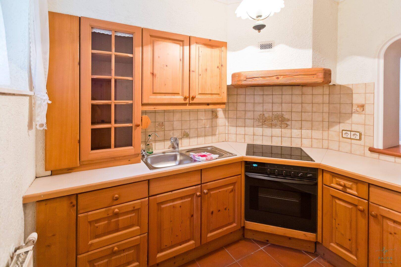 Einbauküche im Landhausstil mit Holzschränken, Backofen und Kochfeld.