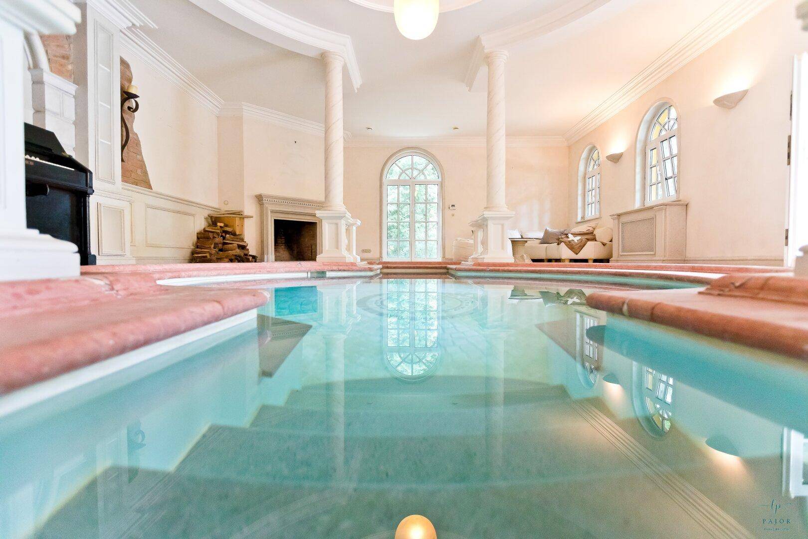 Innenpool mit klarem Wasser, umgeben von Säulen und großen Fenstern für viel Tageslicht.