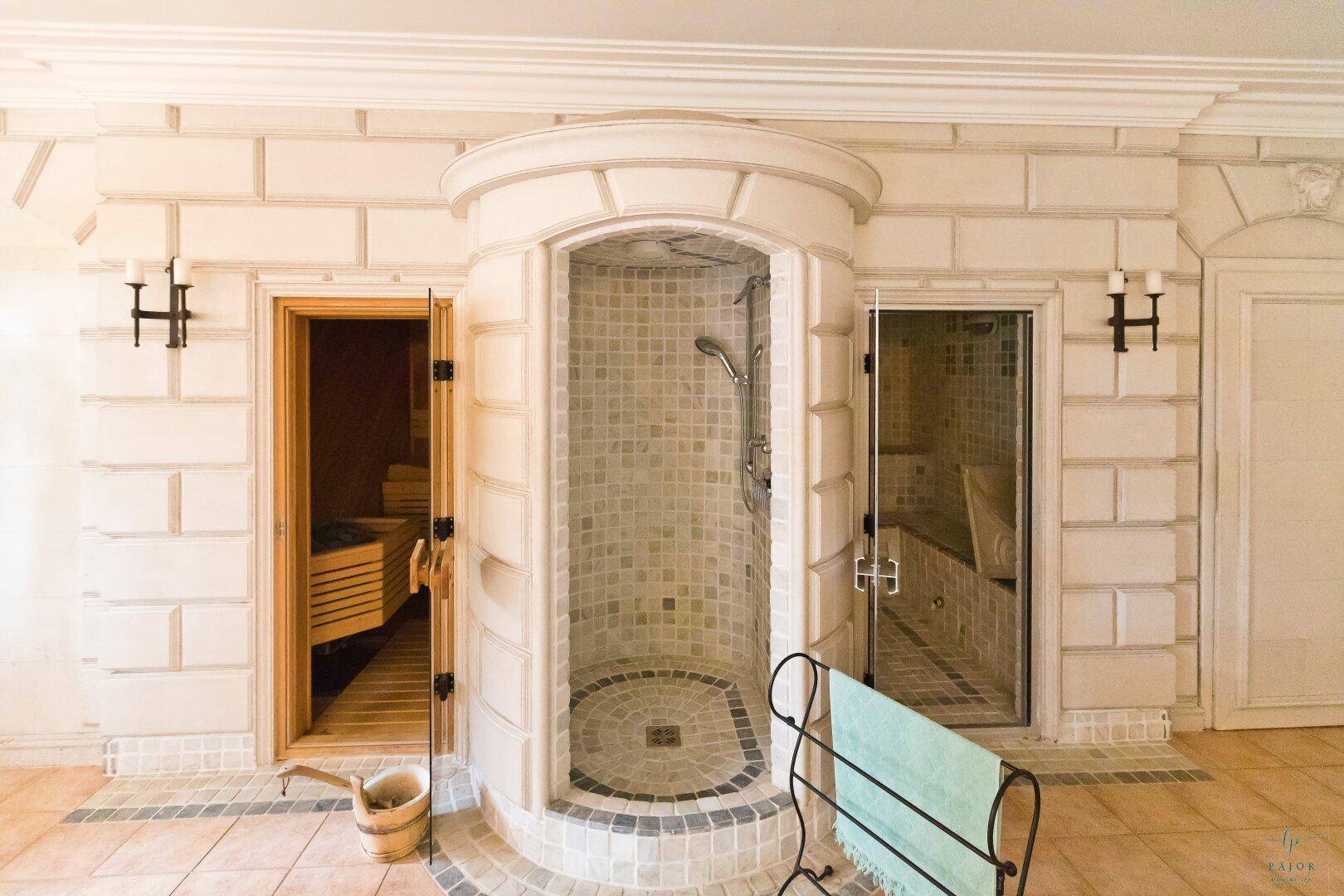 Luxuriöser Wellnessbereich mit zentraler Dusche, Sauna und Dampfbad, umgeben von eleganten Fliesen.