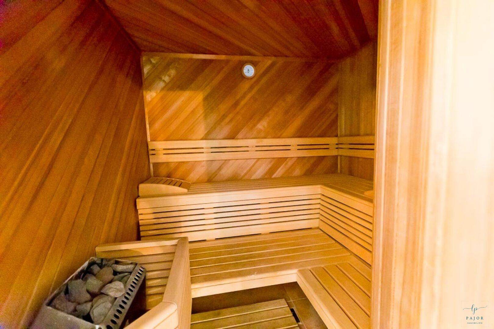 Gemütliche Holzsauna mit mehreren Bänken und einem Saunaofen, ideal zur Entspannung.