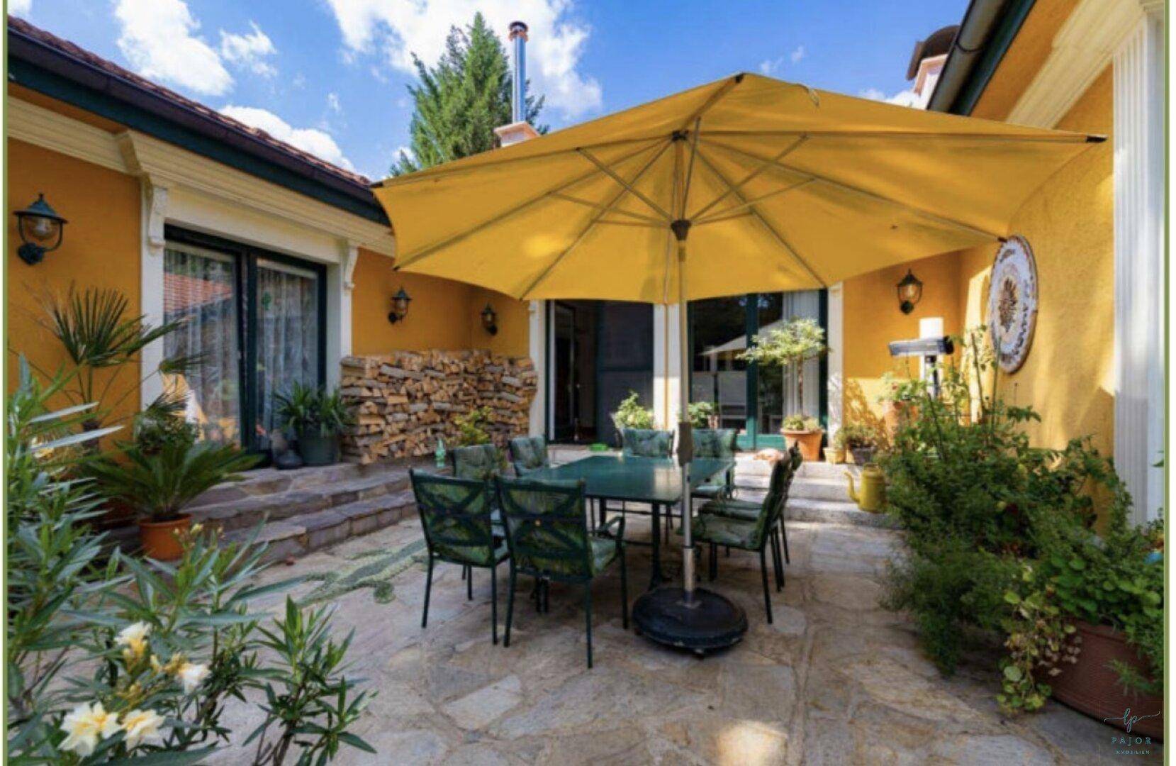 Gemütliche Terrasse mit großem Sonnenschirm, Esstisch und Pflanzen, ideal für entspannte Stunden.