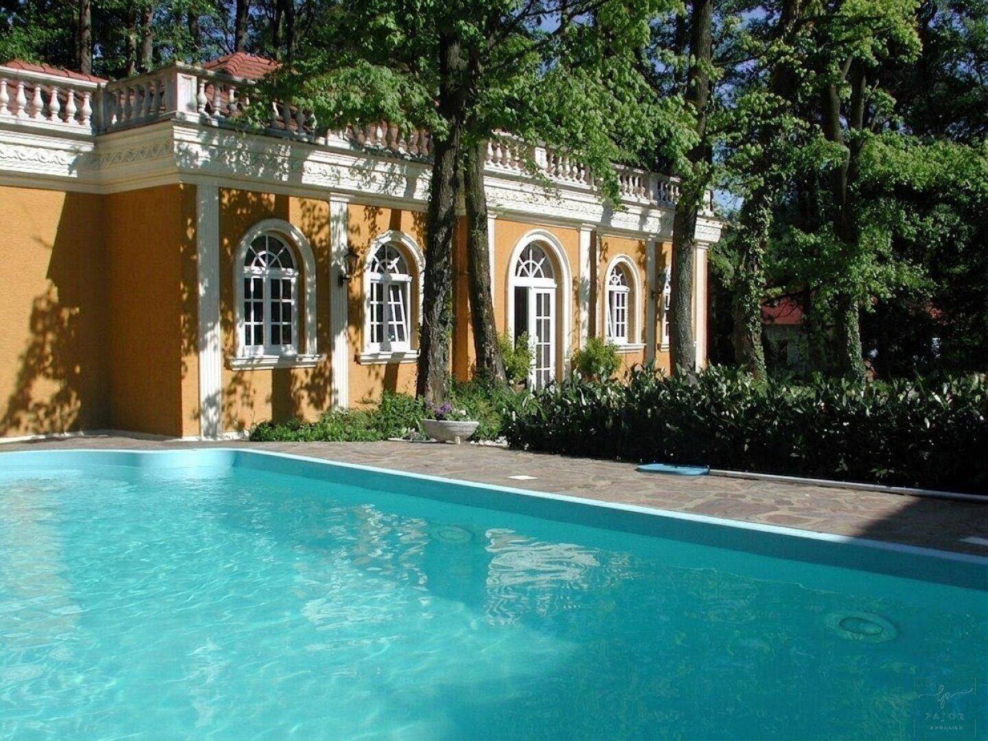 Erfrischender Poolbereich neben dem eleganten Nebengebäude mit Rundbogenfenstern.