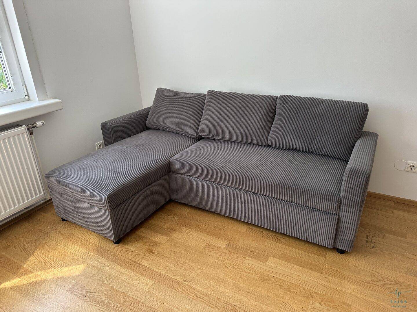Gemütliches Wohnzimmer mit einem modernen grauen Ecksofa und hellem Parkettboden, lädt zum Verweilen ein.