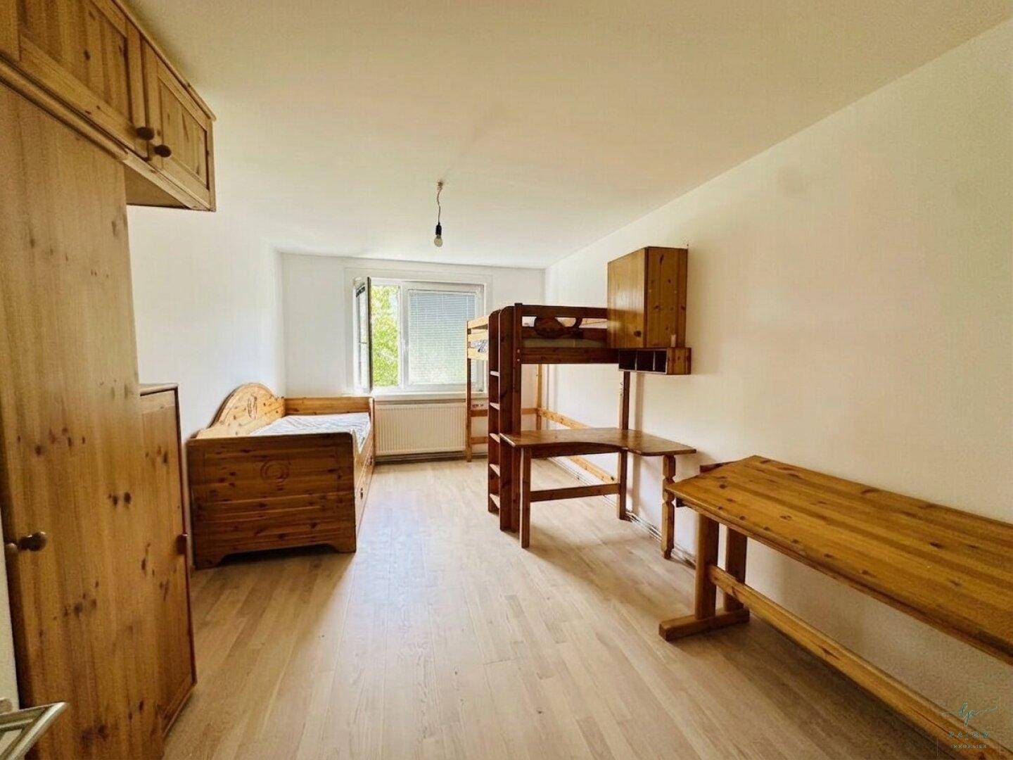 Funktional eingerichtetes Schlafzimmer mit Holzmöbeln, Etagenbett und Schreibtisch, ideal für Kinder oder Gäste.