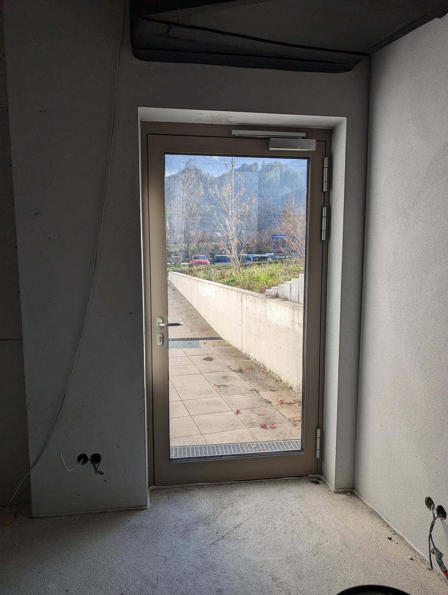 Unfertiger Raum mit einer Glastür, die den Blick auf den Außenbereich freigibt.