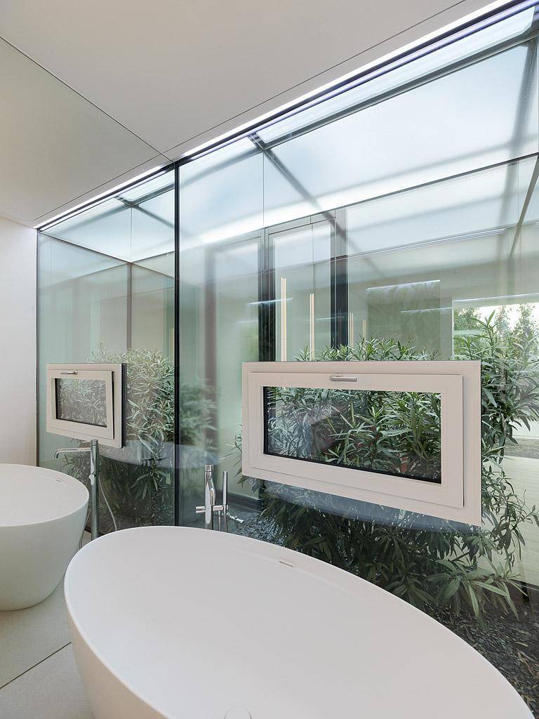 Helles Badezimmer mit freistehender Badewanne und großen Fenstern, die viel Tageslicht hereinlassen.