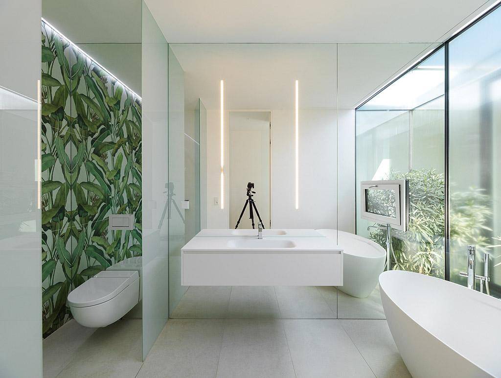 Modernes Badezimmer mit freistehender Badewanne, Doppelwaschbecken und tropischer Tapete.