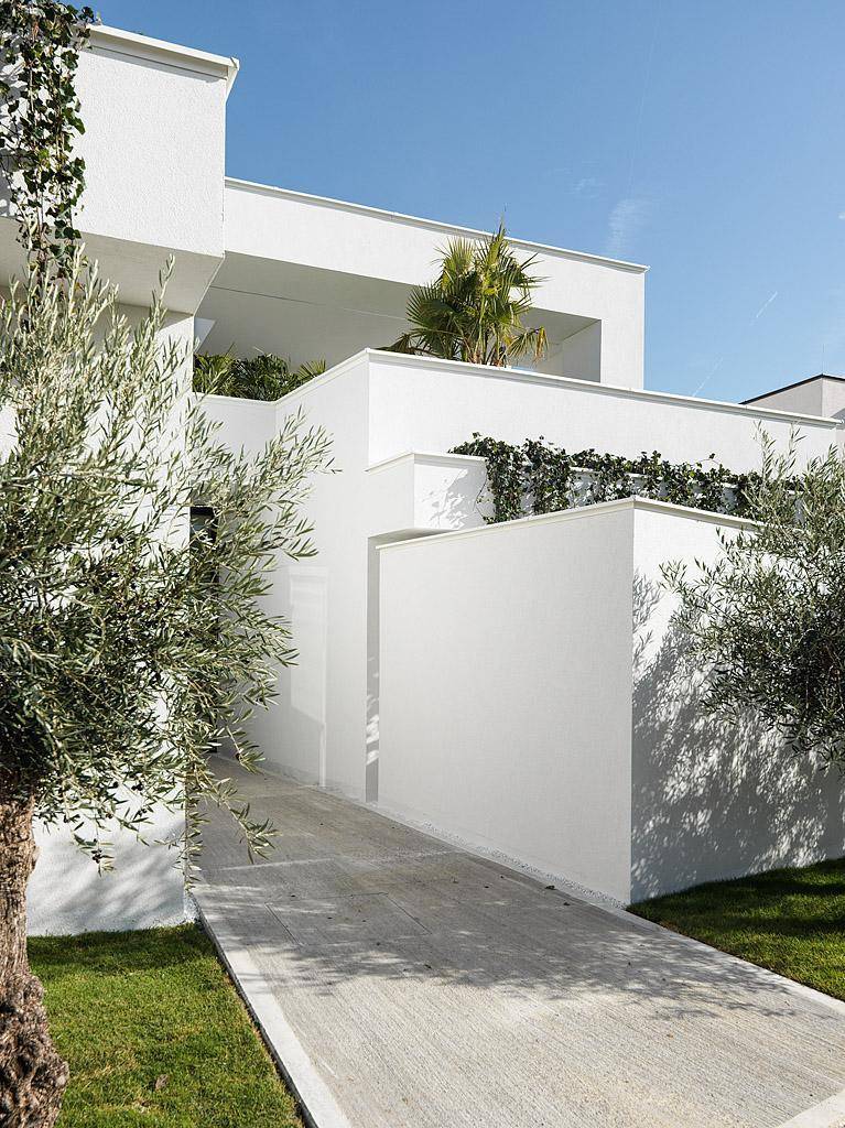 Zeitgenössische Architektur mit klaren Linien, weißen Wänden und Olivenbäumen.