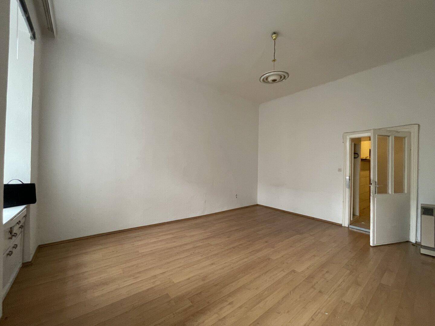 Geräumiger, leerer Raum mit Holzboden und hohen Decken, ideal für vielfältige Nutzungsmöglichkeiten.