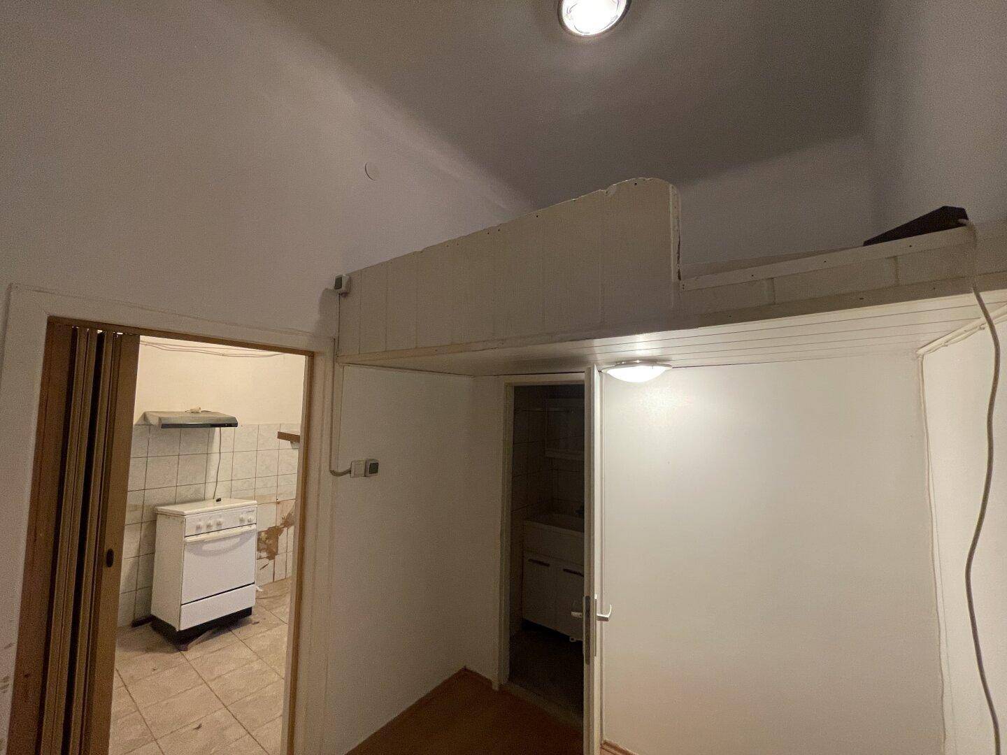 Kleiner Raum mit einer eingebauten Loft-Struktur und Zugang zu einem weiteren Bereich.