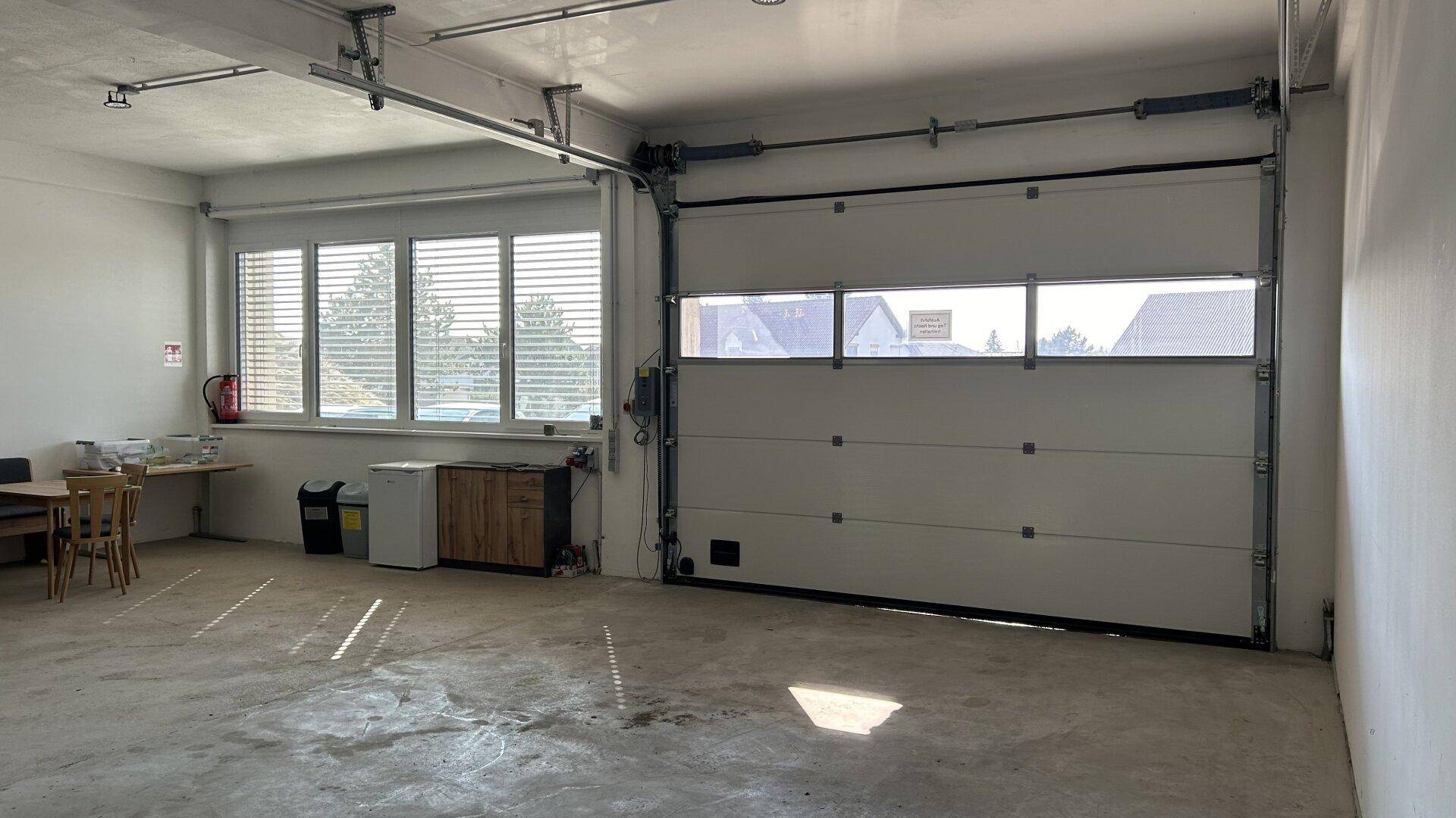 Helle Garage mit großem Rolltor und breiten Fenstern, die viel Tageslicht hereinlassen.