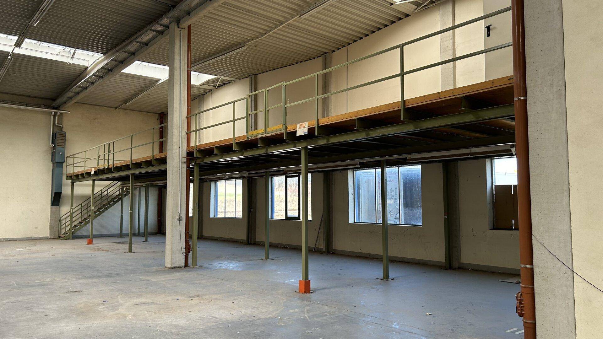 Obere Ebene einer Lagerhalle mit Geländer und Blick auf die Fenster der unteren Etage.