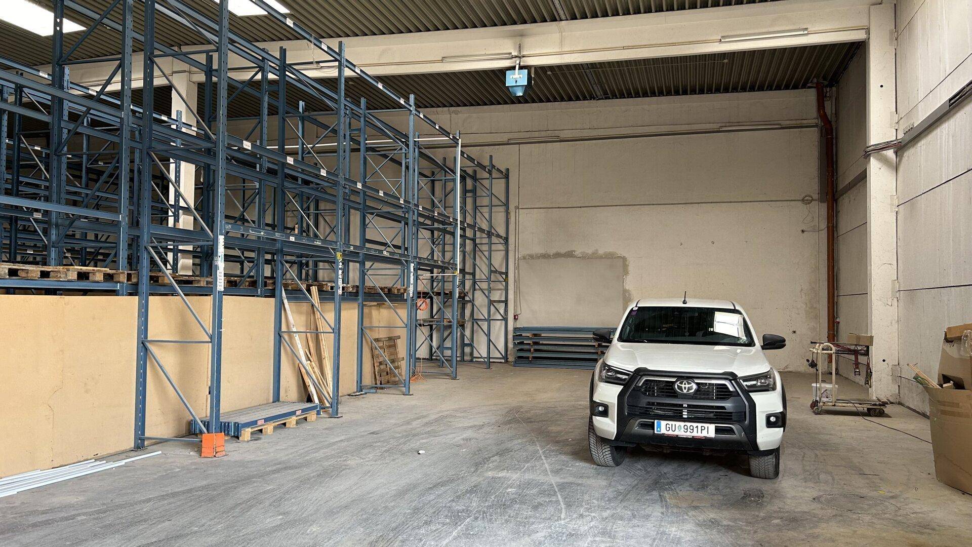 Geräumige Lagerhalle mit hohen Regalen und einem geparkten Fahrzeug, bereit für den Betrieb.