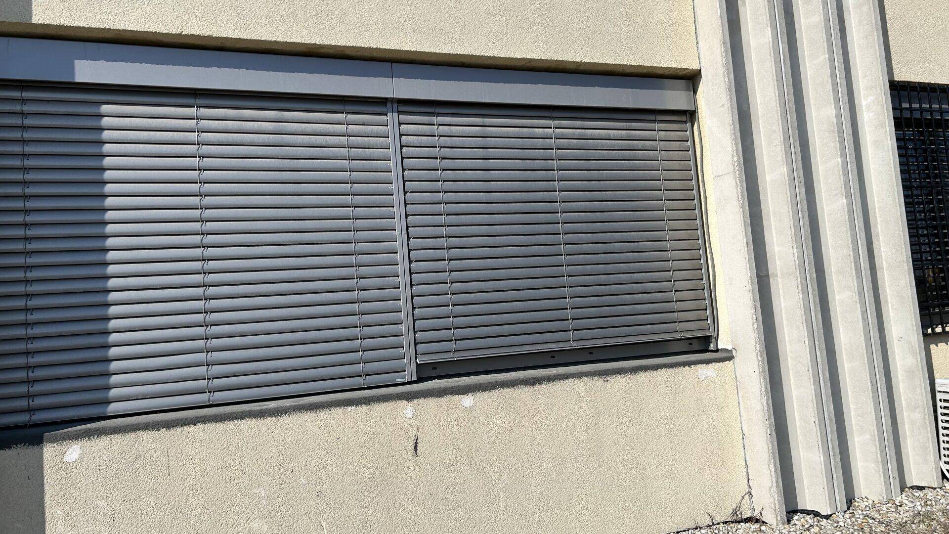 Außenansicht der Fassade mit geschlossenen Jalousien, die Schutz vor Sonne und Einblicken bieten.