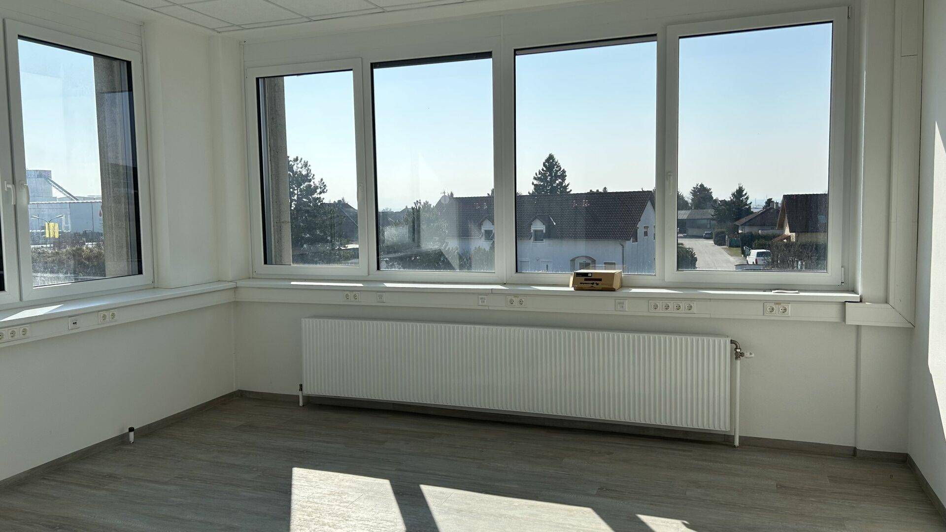 Geräumiges Büro mit großen Fenstern und Blick auf die Umgebung, ausgestattet mit Heizung und Laminatboden.