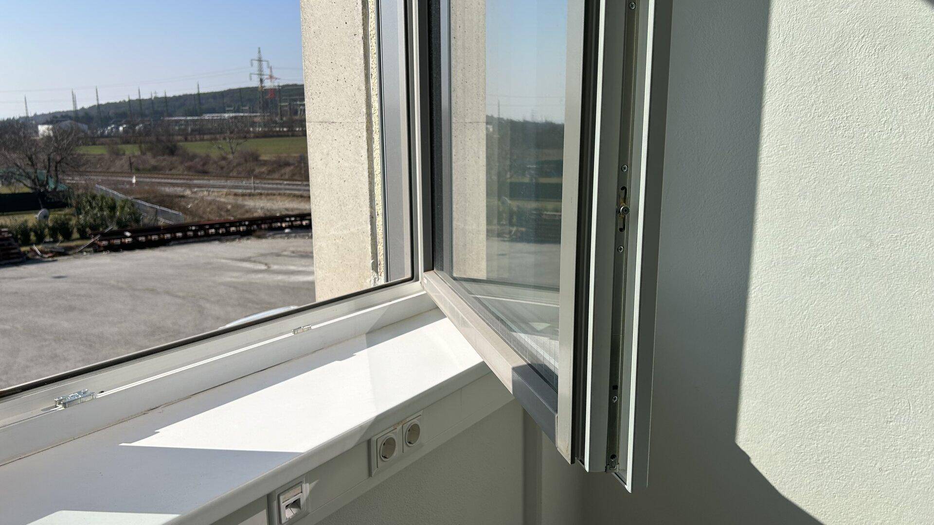 Geöffnetes Fenster mit Blick auf die Umgebung, bietet frische Luft und Tageslicht.