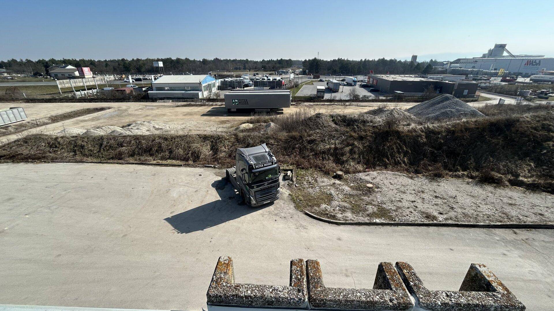 Weitläufiger Außenbereich mit Lastwagen und umliegenden Gewerbeflächen unter klarem Himmel.