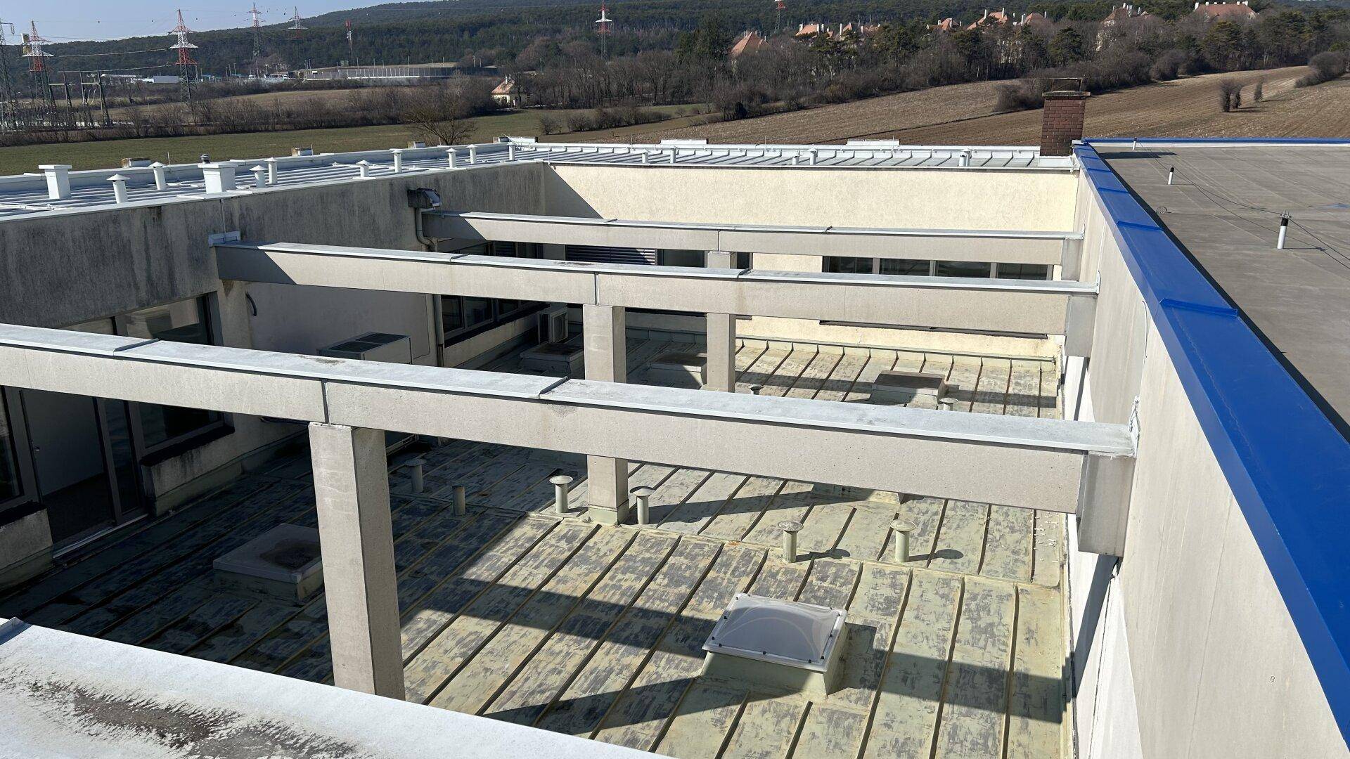 Dachbereich des Gebäudes mit strukturellen Elementen und Blick auf die umliegende Landschaft.