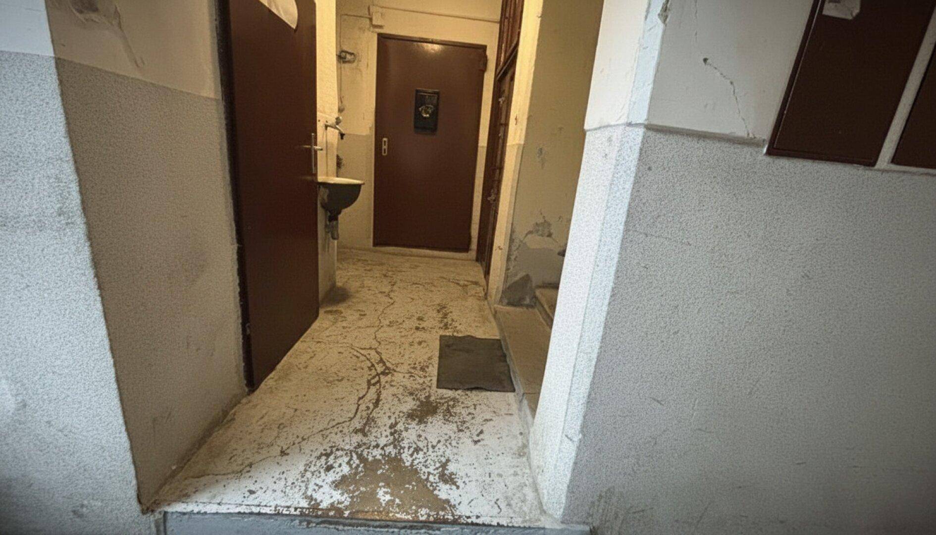 Einfacher Flurbereich mit abgenutztem Boden und mehreren Türen.