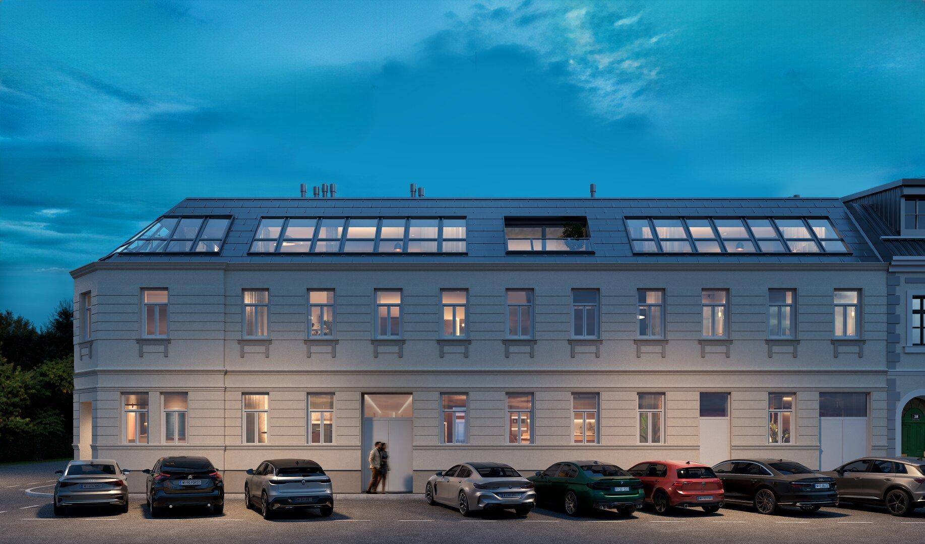 Moderne Gebäudefassade bei Nacht mit beleuchteten Fenstern und Parkplätzen.