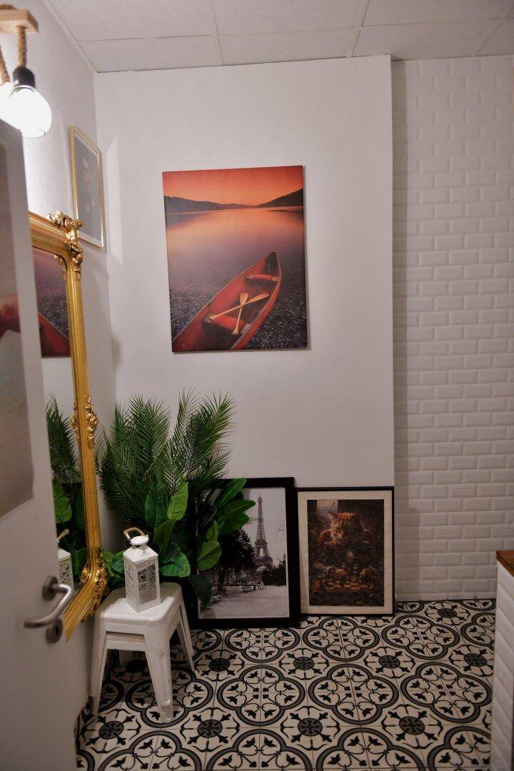 Ein heller Flur mit gemusterten Fliesen, einem großen Spiegel und dekorativen Bildern an der Wand.