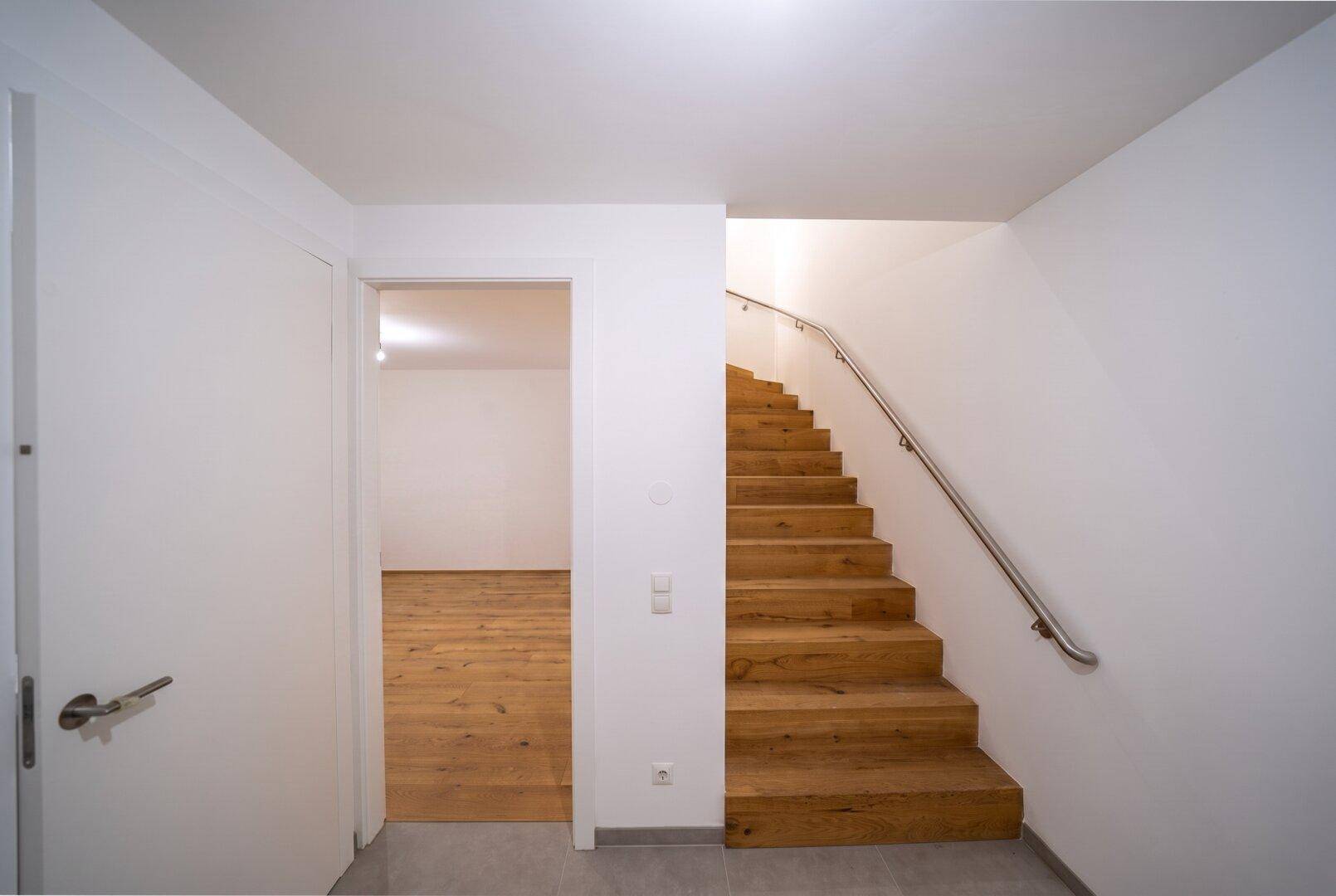 Heller Flur mit Holztreppe und Zugang zu weiteren Wohnbereichen.