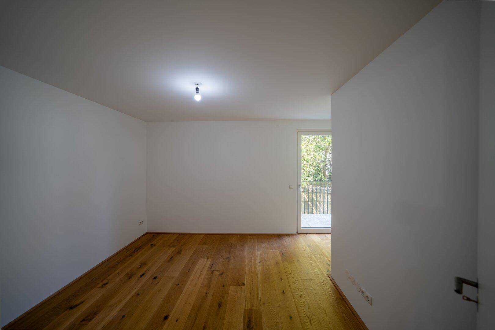 Helles Schlafzimmer mit Holzboden und direktem Zugang zu einem Balkon.