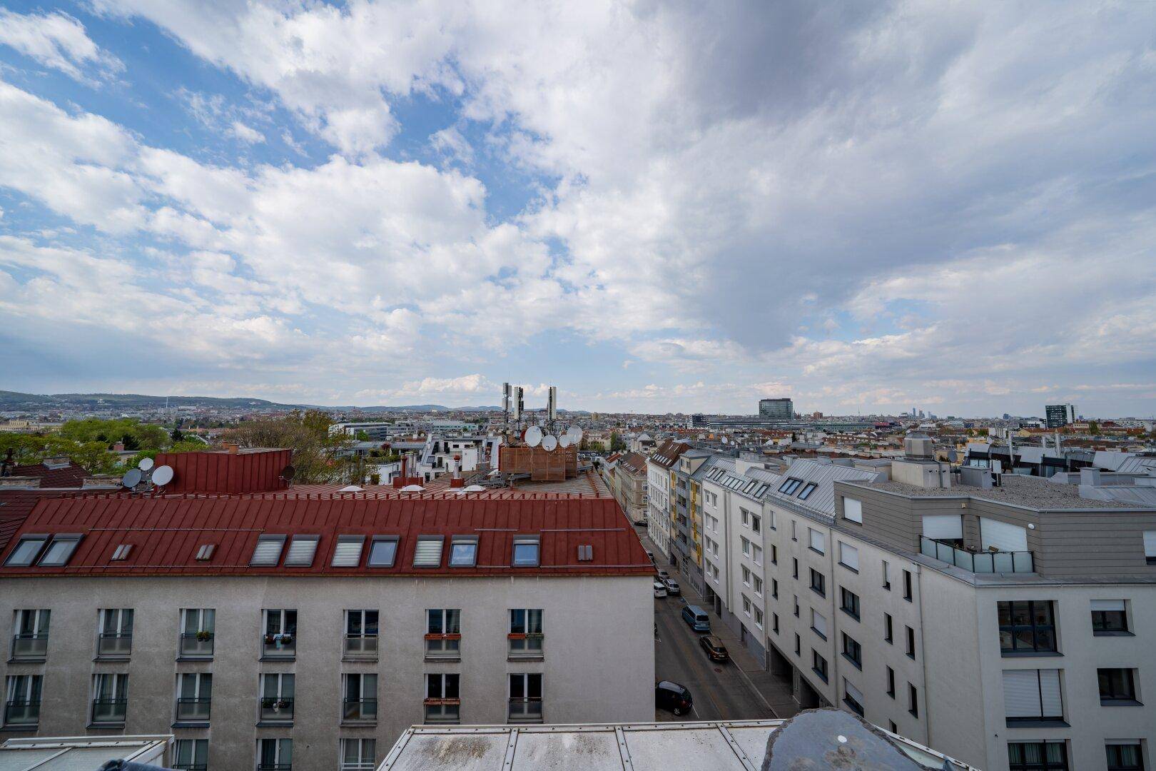 Weitläufiger Blick über die Dächer der Stadt mit Wohngebäuden und bewölktem Himmel.