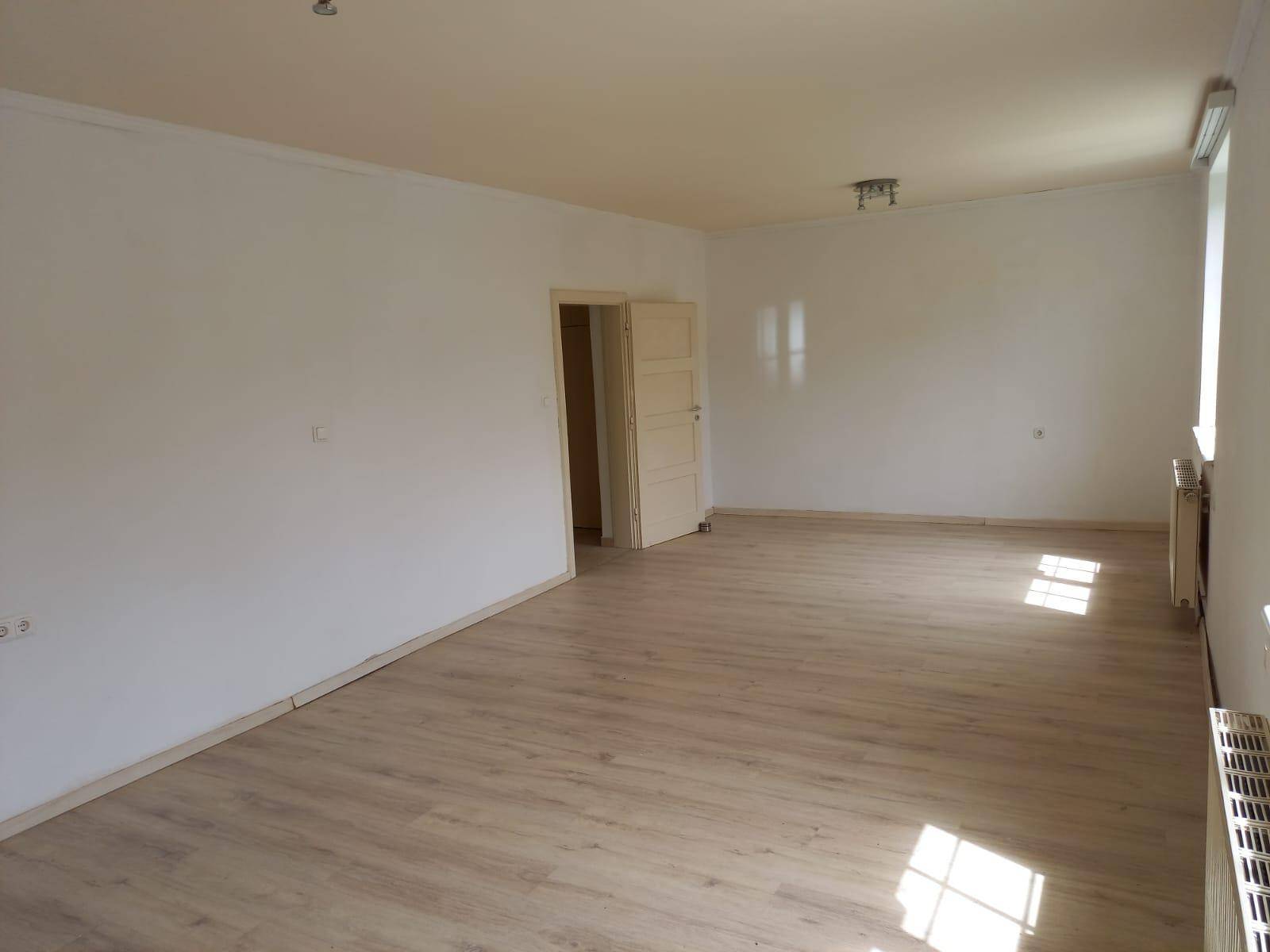 Großes, helles Wohnzimmer mit Laminatboden und viel Platz für individuelle Gestaltung.