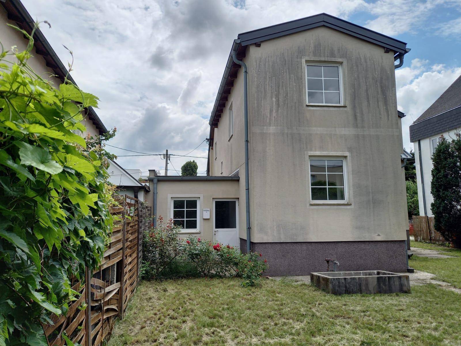 Hinterer Gartenbereich des Hauses mit Rasen, Rosenbüschen und einem kleinen Wasserbecken.