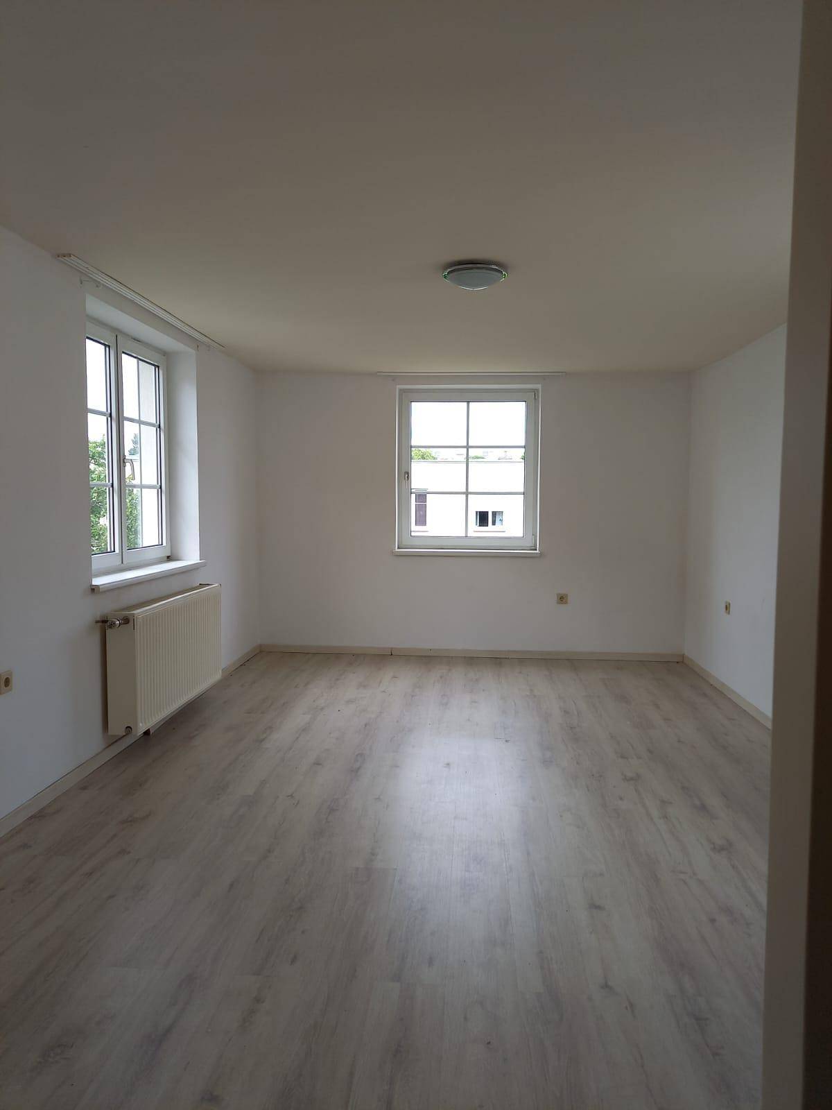 Geräumiges Zimmer mit Laminatboden, zwei Fenstern und viel natürlichem Lichteinfall.