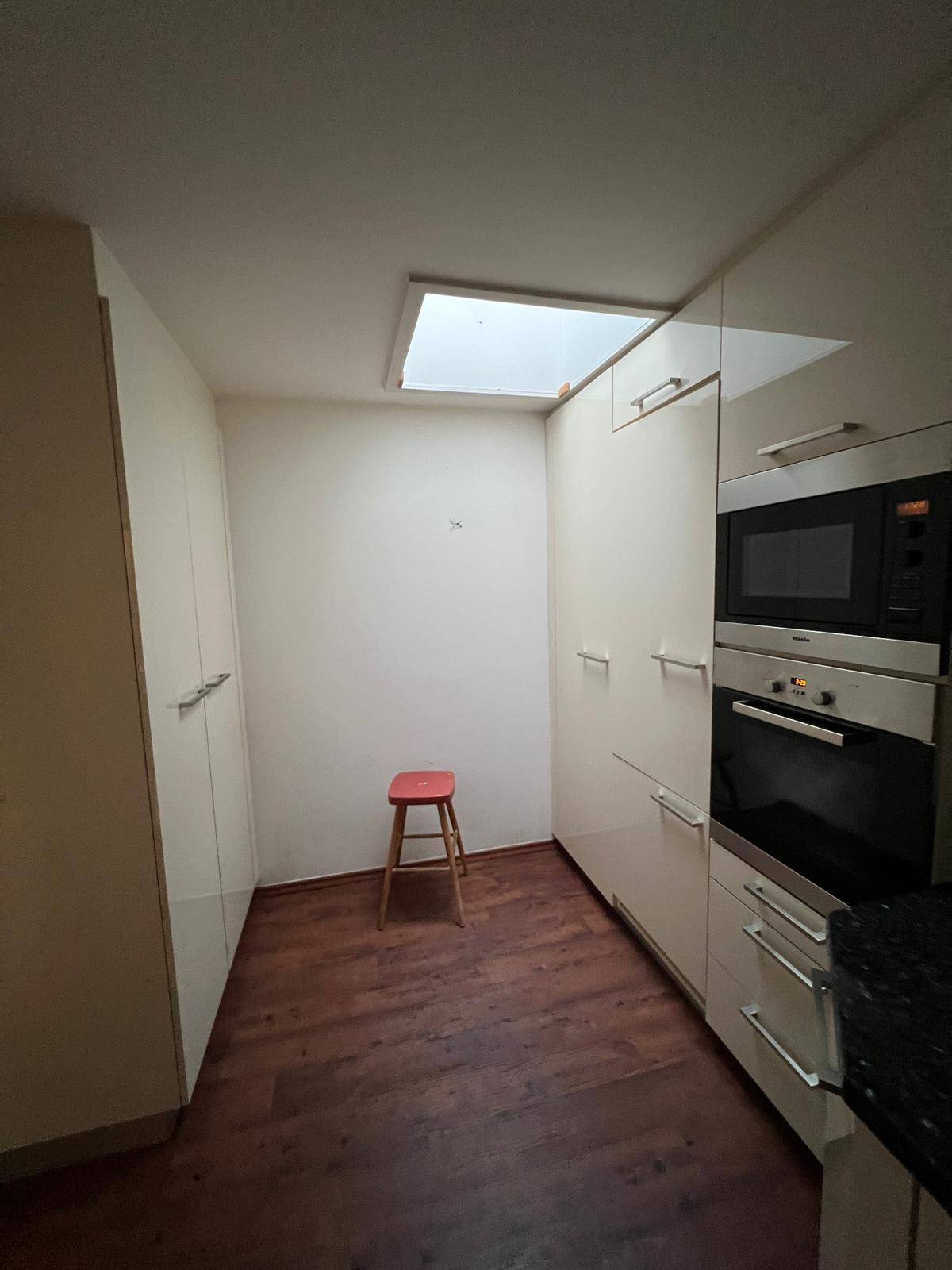 Heller Küchenbereich mit Einbauschränken und einem Dachfenster für natürliches Licht.