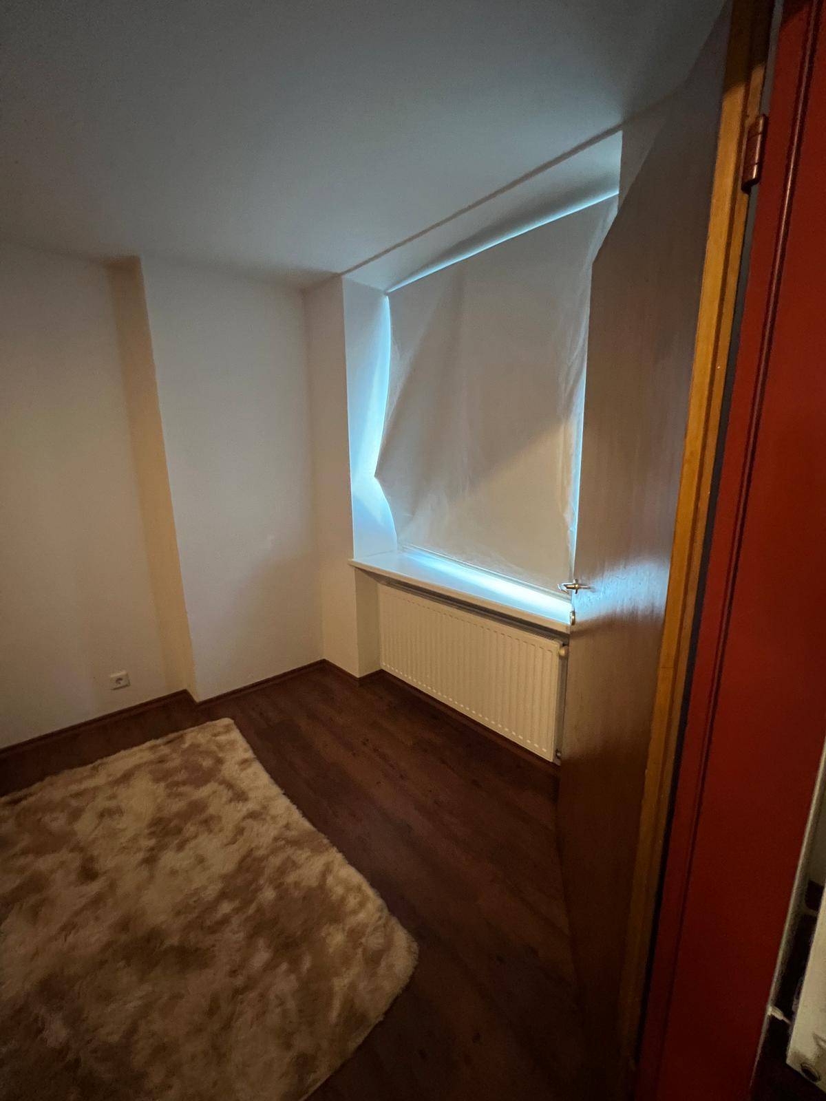 Schlafzimmer mit Fenster, Heizkörper und Teppichboden, bietet eine helle Atmosphäre.