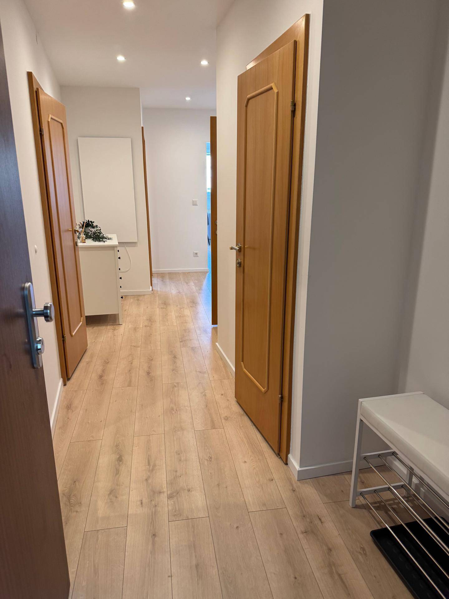 Heller Flur mit Laminatboden und Holztüren, der zu den verschiedenen Räumen führt.