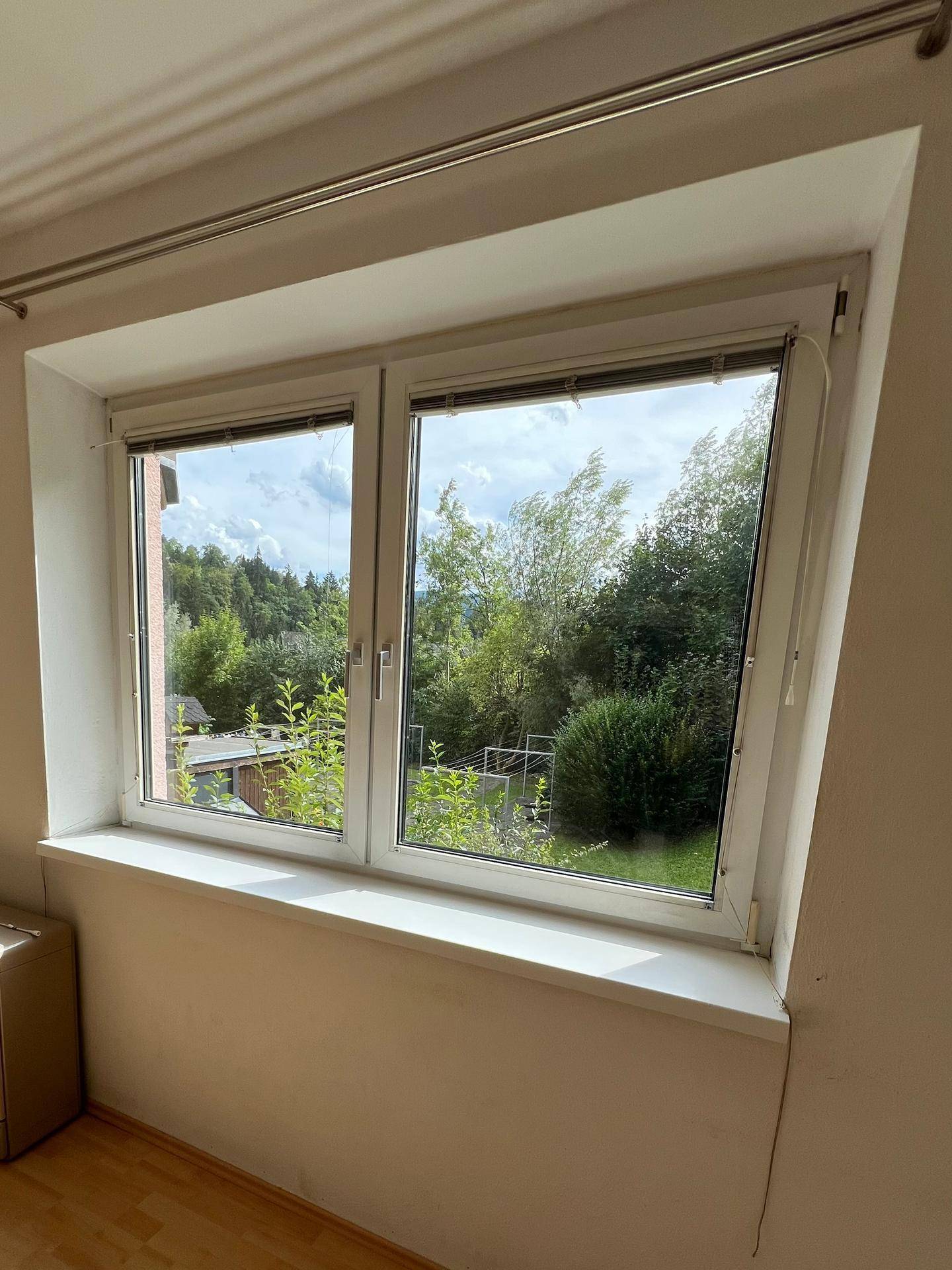 Fenster mit Blick auf grüne Bäume und den Himmel, das viel Tageslicht hereinlässt.