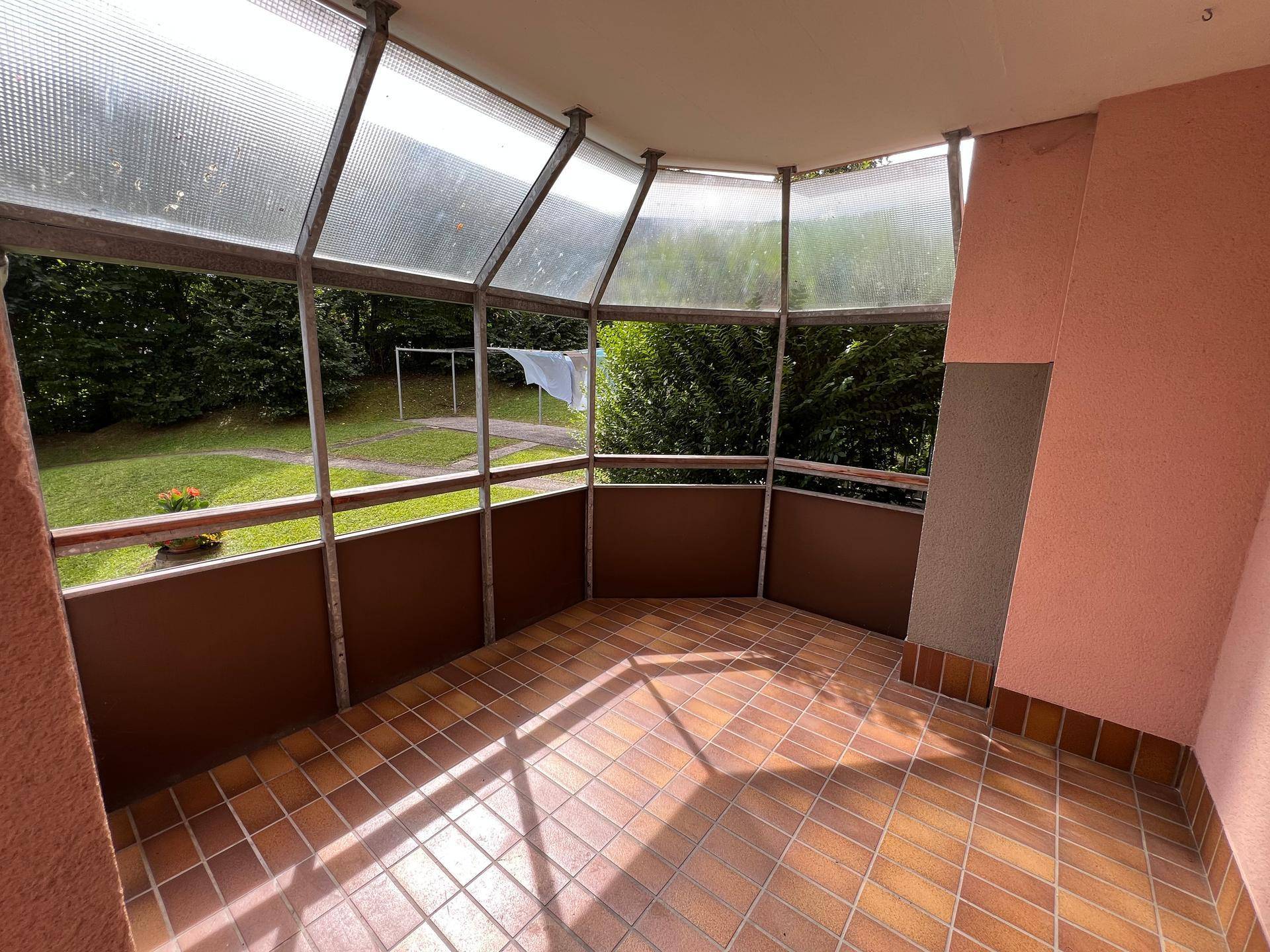 Geräumiger, verglaster Balkon mit Fliesenboden und weitem Blick in die Natur.