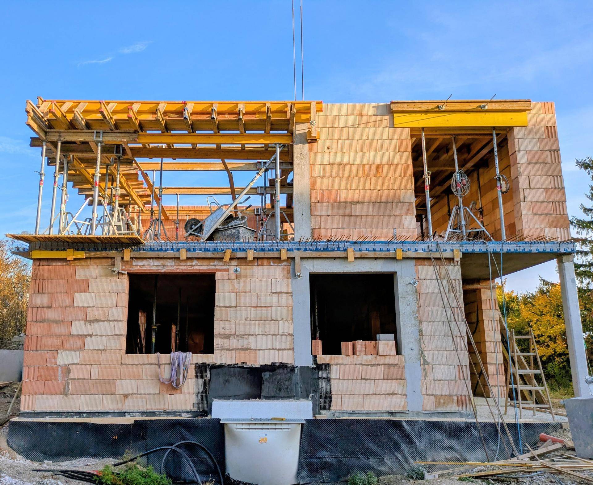 Rohbau eines Gebäudes mit sichtbaren Ziegelwänden und Holzschalung für die nächste Etage.