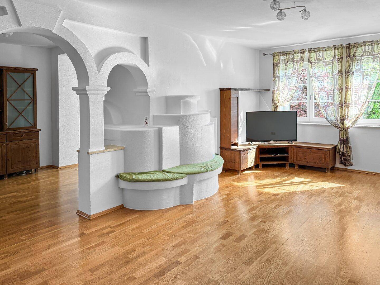 Geräumiges Wohnzimmer mit Holzboden, Kaminofen und traditionellen Holzmöbeln.