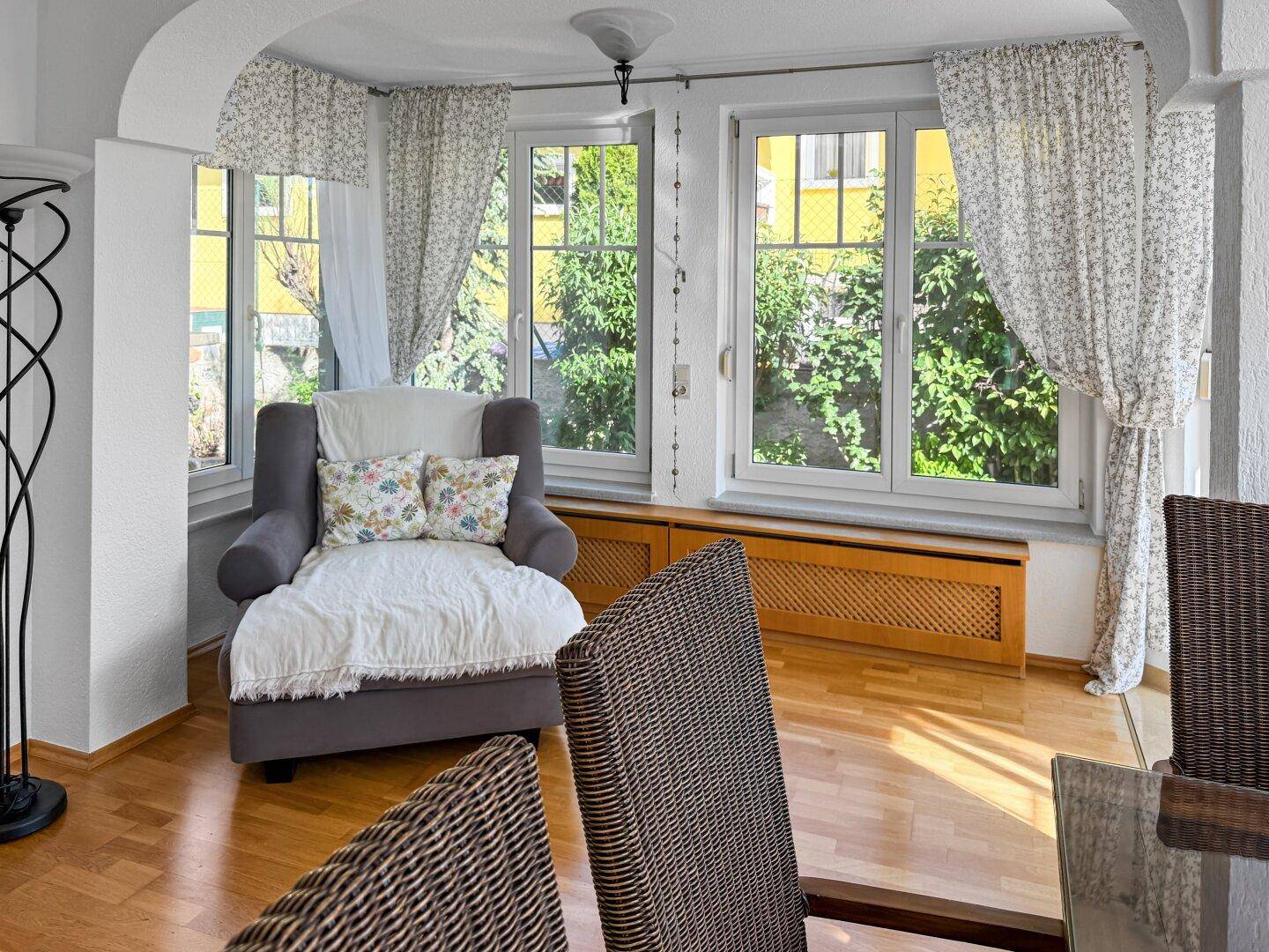 Gemütliche Sitzecke im Wohnzimmer mit großen Fenstern und Blick ins Grüne.
